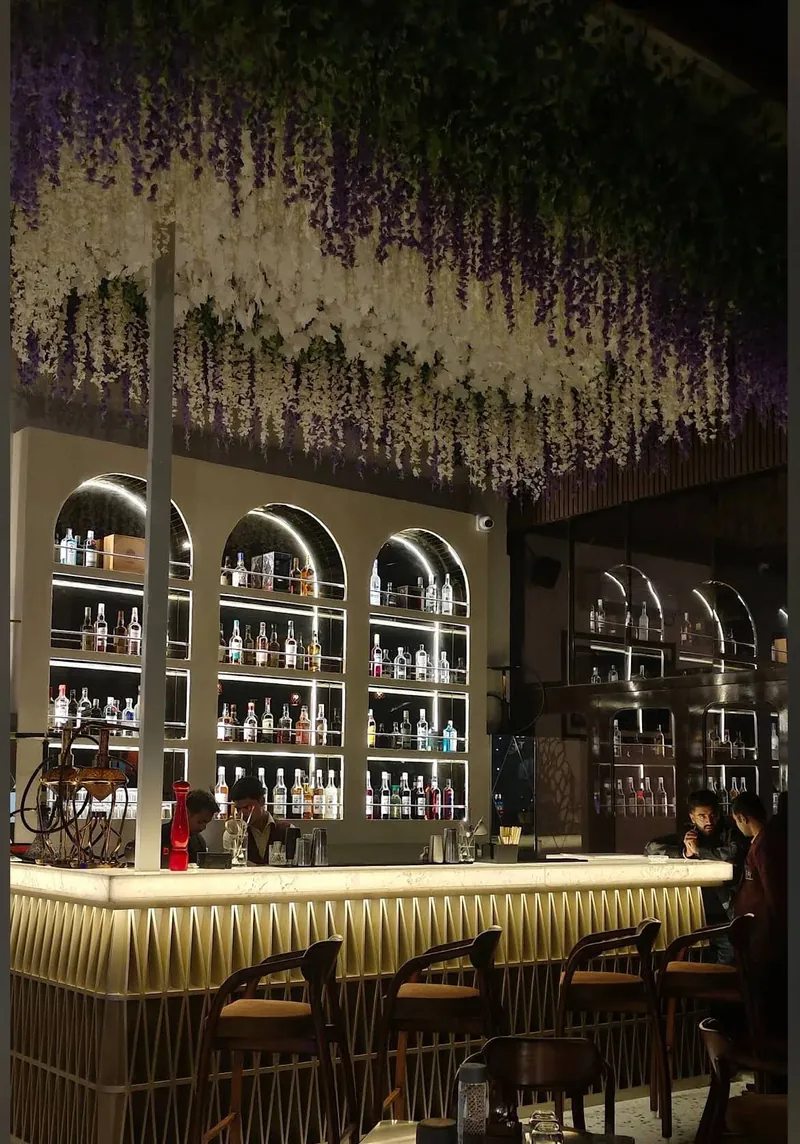 The bar at Eilly Rooftop Revelry, backlit shelves under a floral canopy